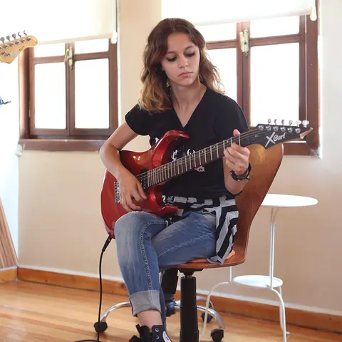 Kırmızı elektro gitarla çalışma yapan öğrenci