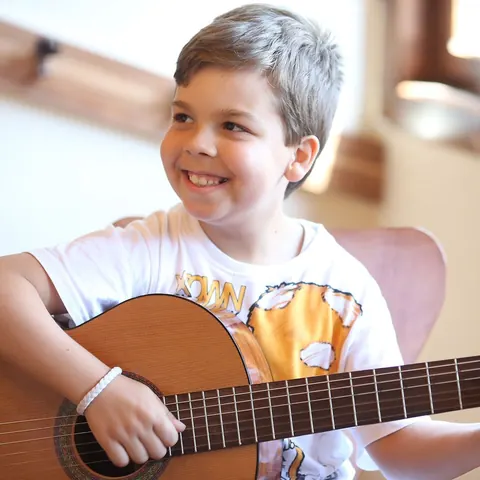 Gitarıyla derse katılan çocuk öğrenci