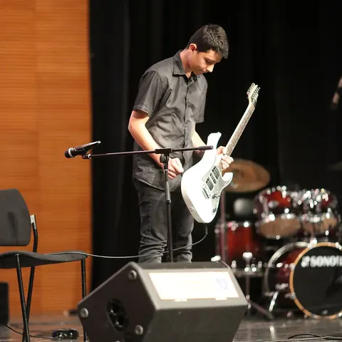 Öğrenci konserinde ayakta elektro gitar performansı