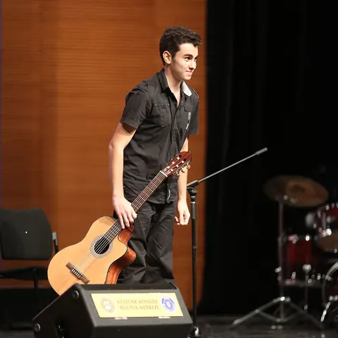 Gitarıyla sahnede seyirciyi selamlayan öğrenci