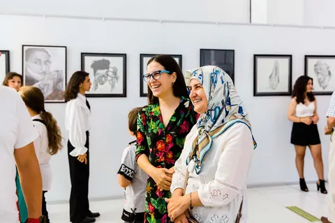 Öğrenci eserlerinin önünde birlikte fotoğraf çektiren konuklar